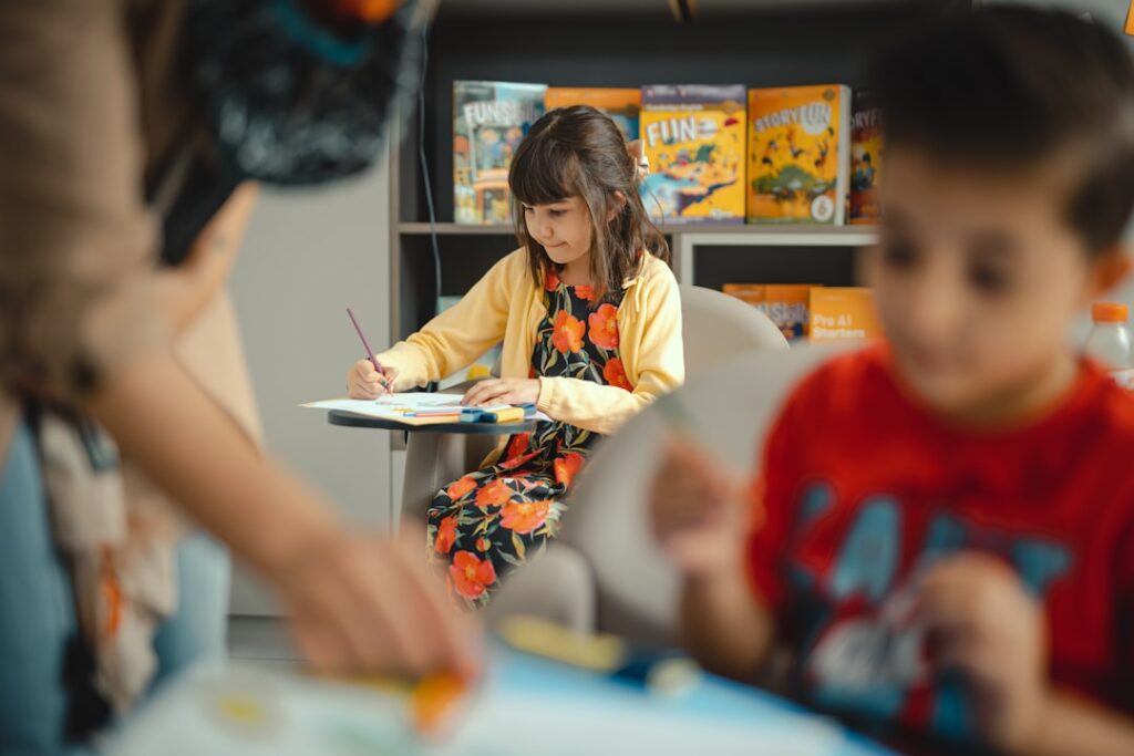 A young child struggles with schoolwork at a kitchen table while a parent offers gentle encouragement.