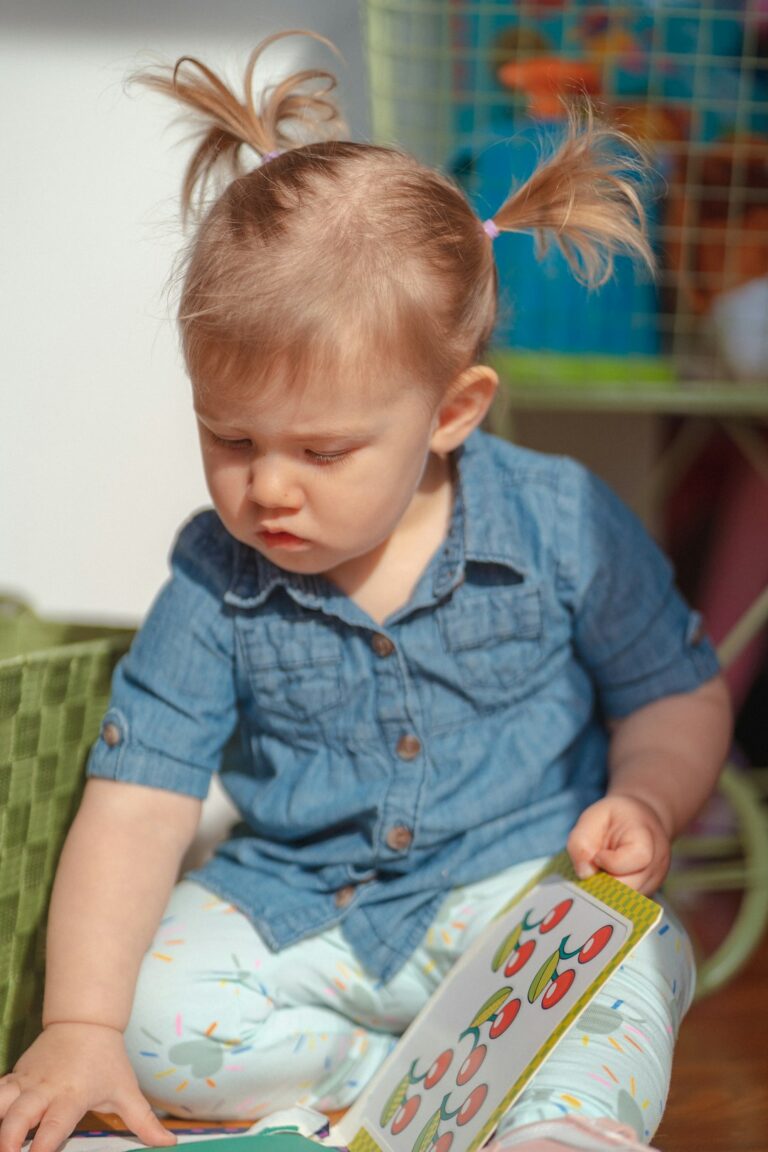 A young child stacking colorful blocks on a carpeted living room floor while an adult watches supportively nearby.